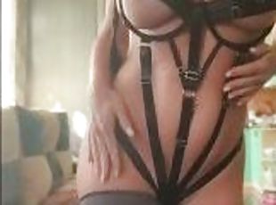 Hot milf in a BDSM costume sweetly fingering her pussy and caressing her whole body